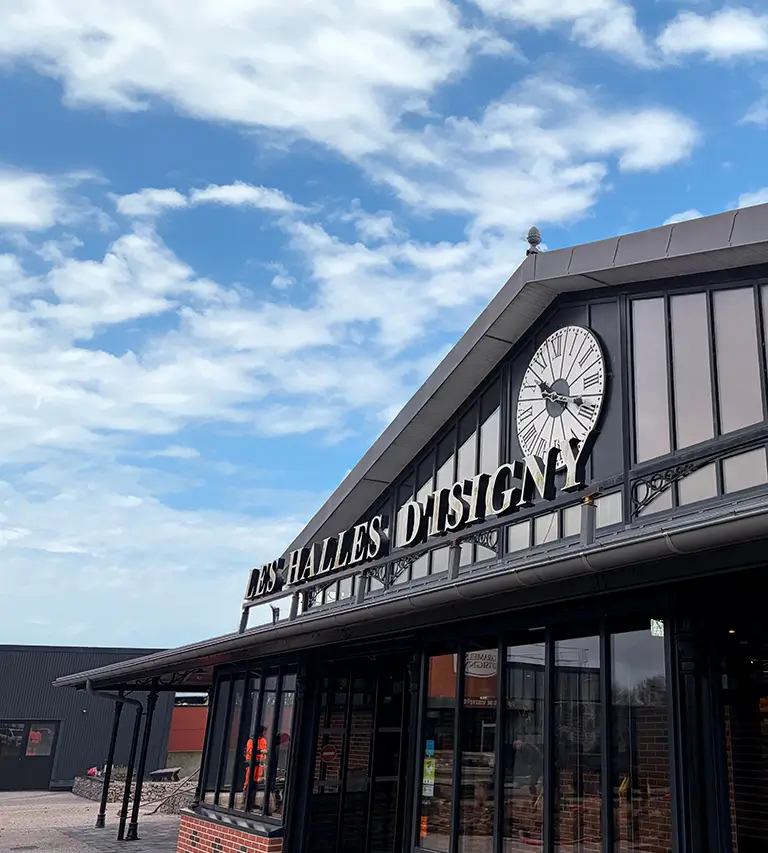 Une photo de la façade du bâtiment des Halles des Caramels d'Isigny avec l'enseigne en gros